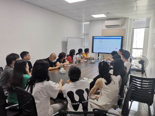 A group of people sitting around a table watching a presentationDescription automatically generated with medium confidence